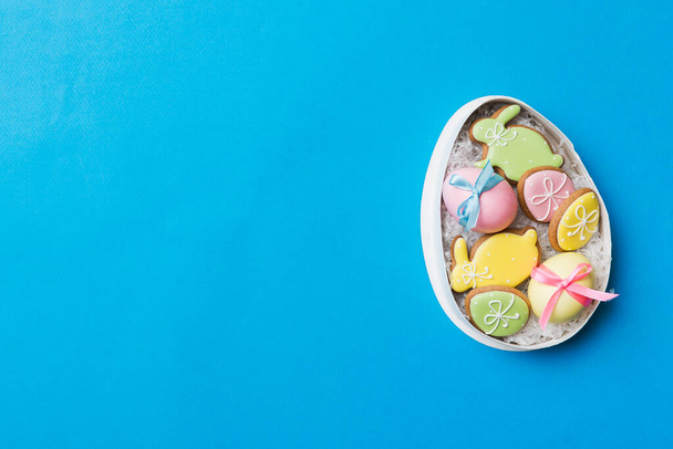 Biscuits de Pâques colorés dans le panier avec des oeufs de Pâques multicolores sur fond coloré. Oeufs de Pâques de couleur pastel. concept de vacances avec espace de copie. - Photo, image