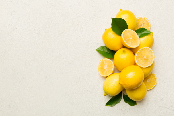 Viele frische reife Zitronen mit grünen Blättern auf farbigem Hintergrund, Draufsicht, Platz für Text. - Foto, Bild