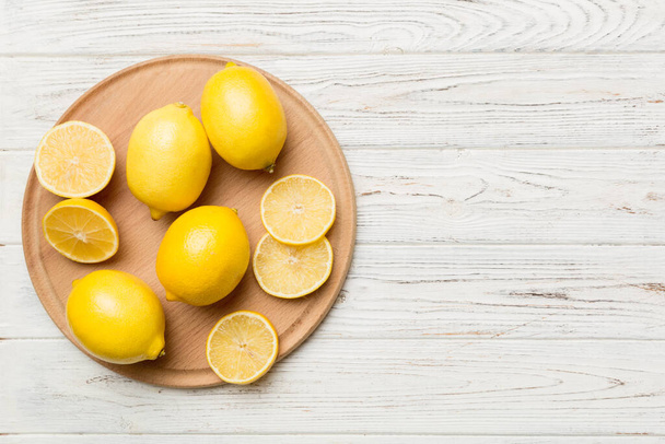 Top view with copy space for fresh and ripe lemons on cutting board. Healthy food background. Elegant background of lemon and lemon slices with squeezer colored background. - Foto, Bild