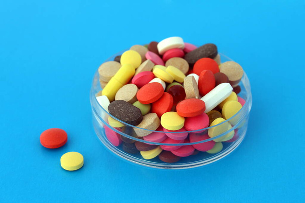 There are many multi-colored pills on a transparent bowl. - Φωτογραφία, εικόνα