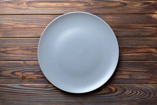 Top view of empty grey plate on wooden background. Empty space for your design. - Foto, immagini