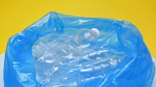 plastic bottles in garbage bag isolated on yellow  - Photo, Image