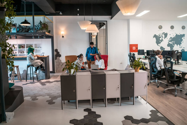 group of casual multiethnic business people taking break from the work doing different things while enjoying free time in relaxation area at modern open plan startup office. High quality photo - Foto, afbeelding