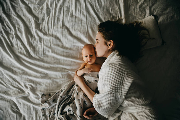 Madre e neonato sdraiati a letto su lenzuolo bianco. - Foto, immagini