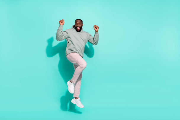 Full length body size view of attractive cheerful lucky guy jumping having fun isolated over bright teal turquoise color background - Zdjęcie, obraz