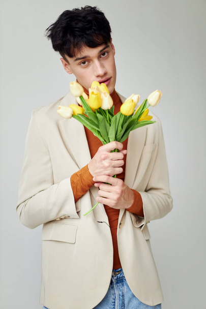 Photo young boyfriend in white jacket with a bouquet of yellow flowers elegant style Lifestyle unaltered - Foto, afbeelding