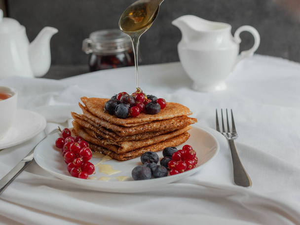 pancakes with forest berries red currant blueberries and tea  - Photo, Image