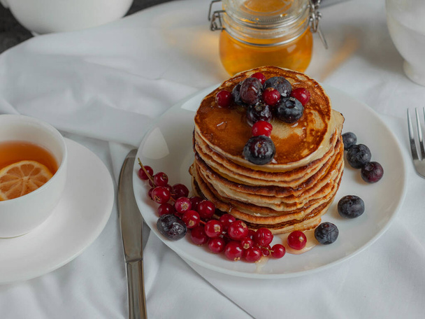 pancakes with forest berries red currant blueberries and tea  - Foto, Imagen