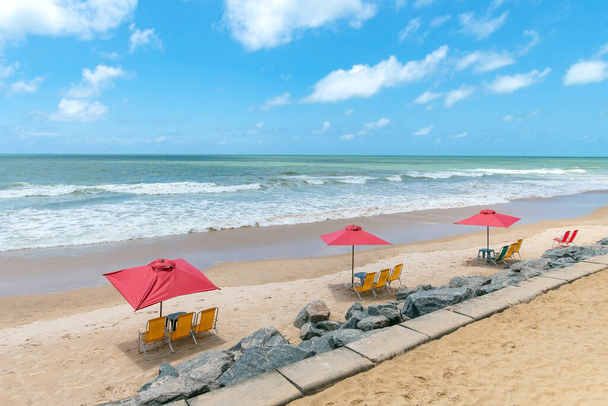 Sombrillas y sillas en la arena de una hermosa playa turística en un día soleado. Playa de Boa Viagem en Recife, PE, Brasil. - Foto, imagen