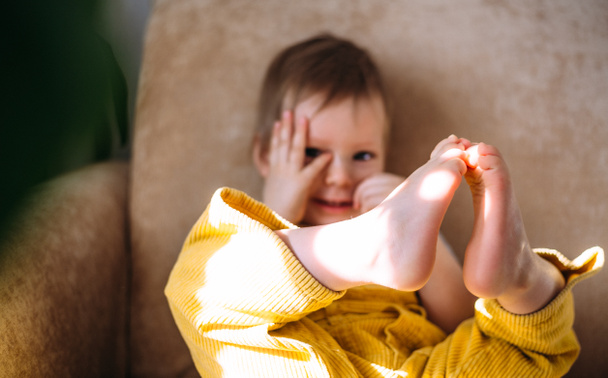 Funny little child is having fun, playing with soft toys on the couch at home. - Fotoğraf, Görsel