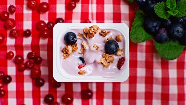 top view of fresh berries on top of yogurt with granola in plastic container  - Foto, Imagen