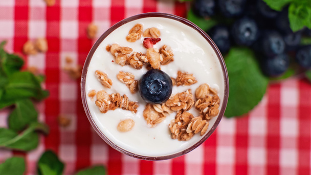bovenaanzicht van bosbessen en knapperige granola bovenop verse yoghurt - Foto, afbeelding