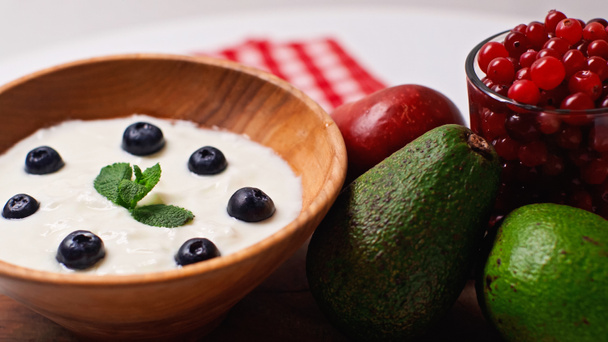 frutas perto de tigela de madeira com iogurte e mirtilos em branco - Foto, Imagem
