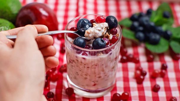 cropped view of man holding spoon with fresh yogurt and berries - Zdjęcie, obraz
