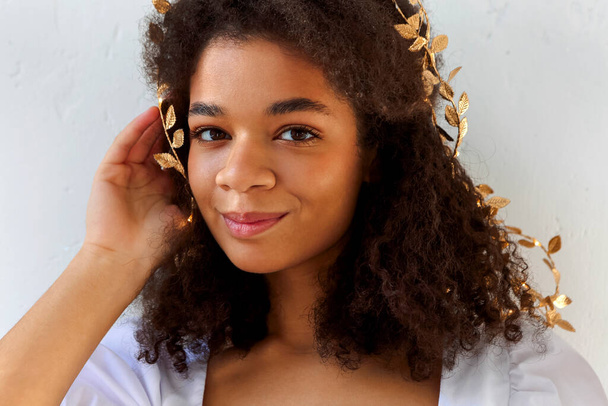Közelkép portré aranyos afro-amerikai nő göndör haj arany levél fejpánt néz kacér kamera elszigetelt fehér, szép nő melanin gazdag bőr tónusú. Természetes afrikai szépség - Fotó, kép