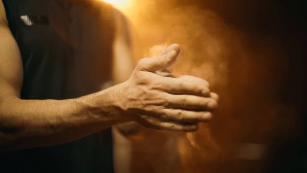 Обрезанный вид размытого спортсмена, наносящего тальк на руки на темном фоне - Фото, изображение