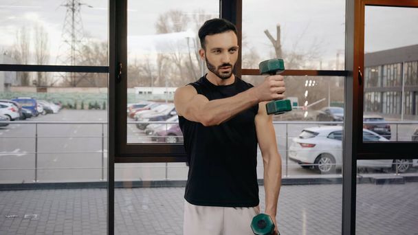 Athletic sportsman training with dumbbells in gym  - Fotó, kép