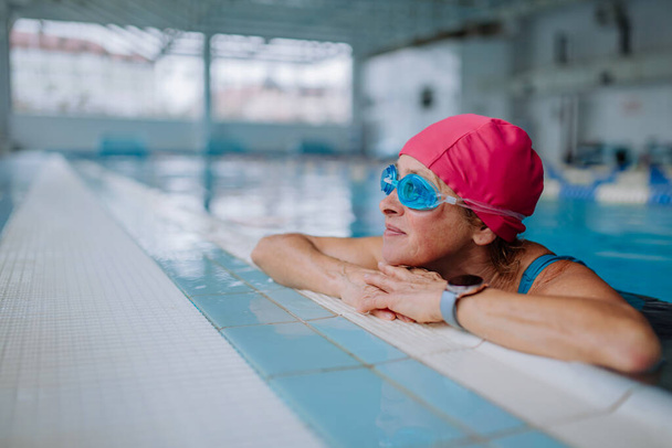 Happy senior woman in swimming pool, leaning on edge. - Photo, Image