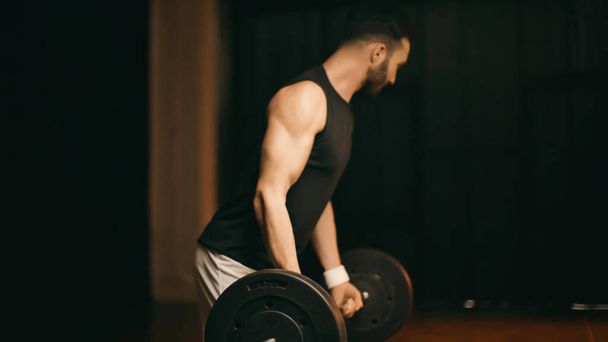 Blurred sportsman training with barbell on dark background - Photo, Image
