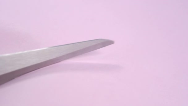 Using scissors to cut colored pink paper. Macro shot. DIY creative playing concept - Materiał filmowy, wideo