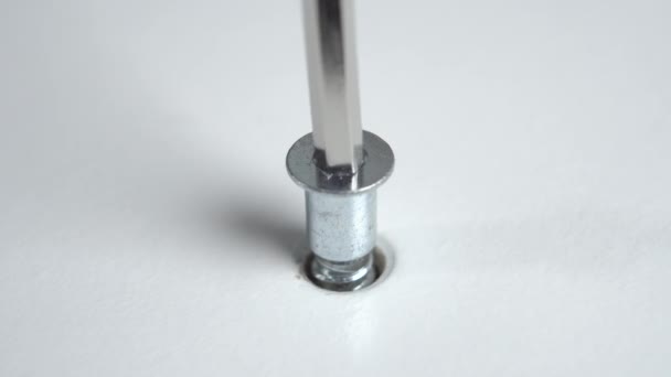Fixing the furniture screw with a hex wrench. Using an allen key to assemble a white nightstand. Macro - Imágenes, Vídeo