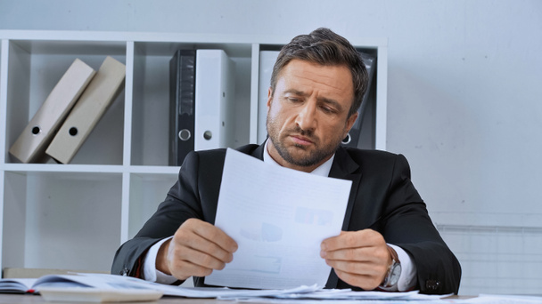 upset businessman looking at document while working in office - Photo, Image