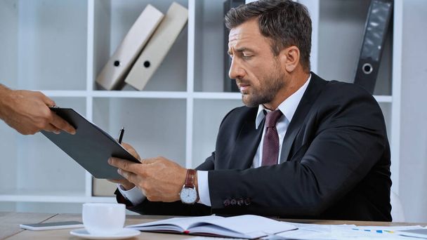 businessman signing document on clipboard in hands of assistant - Foto, Bild