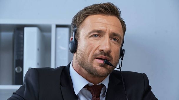 άνδρας με επίσημη ένδυση και ακουστικά που εργάζονται στο τηλεφωνικό κέντρο - Φωτογραφία, εικόνα