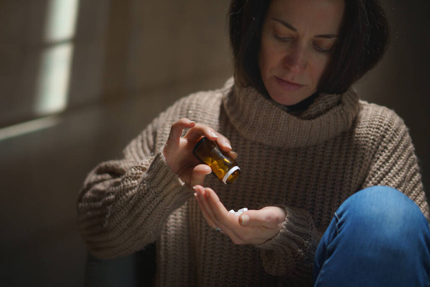Depressed woman taking pills, mental health concept. - Фото, изображение