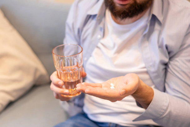 Young man holding a glass with water and pills in his hands pill in her hand medical prescription - 写真・画像