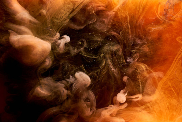 Oranje rook op zwarte inkt achtergrond, kleurrijke mist, abstracte kolkende oceaan zee, acrylverf pigment onderwater - Foto, afbeelding