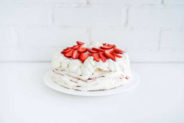 Delicious cake with cream cheese and strawberries. Beautiful serving on a white brick background - Foto, immagini