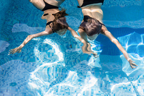 Tini lányok úszás a víz alatt egy hotel medencéjében élvezi a nyári szüneteket - Fotó, kép