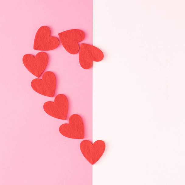 Valentine's Day love creative scene of neatly arranged red hearts in the shape of the big half heart on divided pink pastel and white background. Minimal concept. Flat lay. Copy space. - Фото, изображение