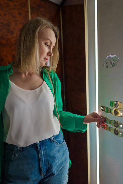 Egy nő nyomja meg a gombot a liftben.. - Fotó, kép