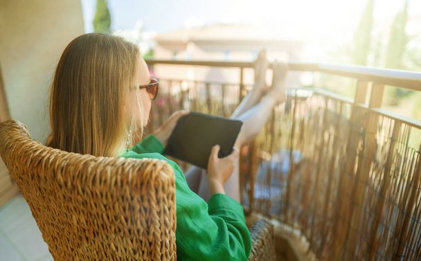 Vrouw met tablet pc geniet van de zomer op het balkon. - Foto, afbeelding