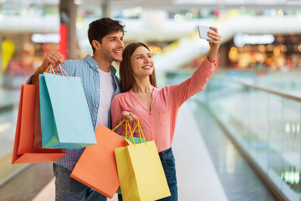 Veselí manželé nakupování dělat selfie pomocí smartphonu v hypermarketu - Fotografie, Obrázek