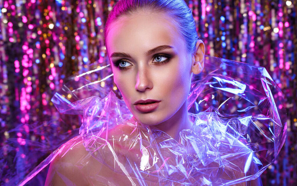Beauty portrait of a High Fashion woman in colorful bright neon lights posing On colourful vivid sequin background - Fotó, kép