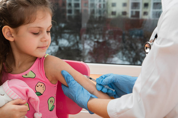 vaccinatie van kinderen. Dokter die een kind onderzoekt in een ziekenhuis - Foto, afbeelding