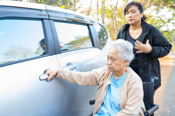 Aide soignante et soutien asiatique femme âgée patient assis sur fauteuil roulant se préparer obtenir à sa voiture. - Photo, image