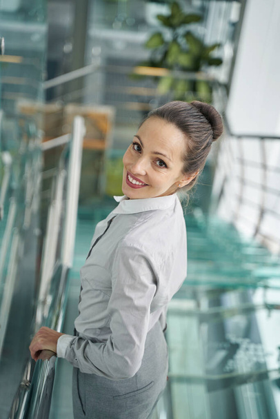 Joyful female posing for camera on glass staircase - Fotografie, Obrázek