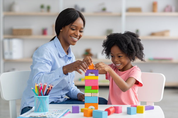 Adorable enfant noir et spécialiste du développement de l'enfant jouer avec des briques - Photo, image
