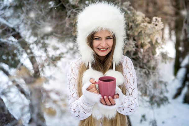 portret atrakcyjnej kobiety ze spacerkiem kawowym po zimowym parku - Zdjęcie, obraz