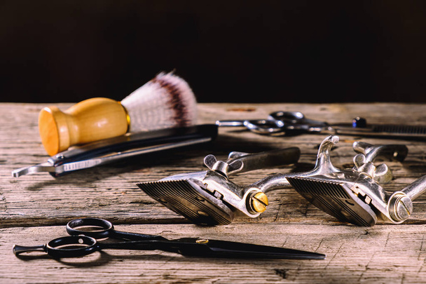 На деревенской деревянной выветриваемой поверхности находятся старые парикмахерские инструменты. Винтажные ручные волосы клиппер гребень бритвы бритвы щетка для бритья щетка парикмахерские ножницы. hhhontal. - Фото, изображение