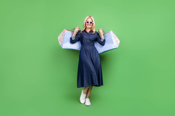 Full body photo of mature attractive lady good mood shopping store isolated over green color background. - Zdjęcie, obraz