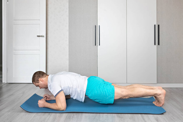 Een sterke, gezonde man met spieren, thuis aan het trainen. Fitness thuis. Yoga. - Foto, afbeelding