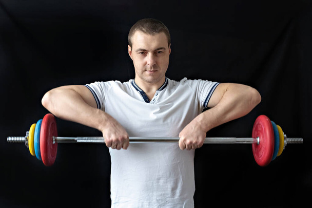 Un hombre fuerte y sano con músculos, entrenando en casa con una barra. Fitness en casa - Foto, imagen