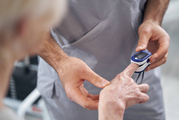 Doctor applying pulse oximeter to patient finger - Фото, зображення