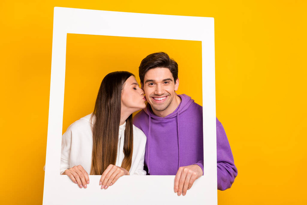 Portrait of two lovely persons picture paper frame kiss cheek isolated on yellow color background. - Фото, зображення