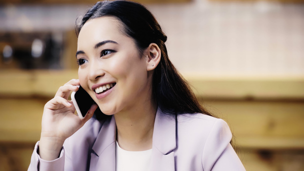 cheerful asian woman in suit talking on smartphone in cafe  - Foto, Imagem